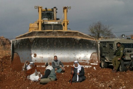 Palestinian farmers sit in front of a di